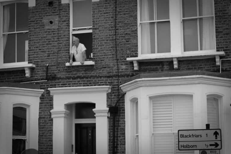 Man looking out of window, Kings Cross Road, London, black and white