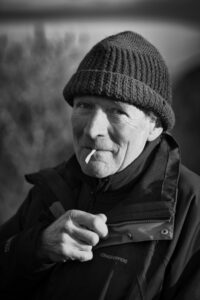 Portrait of older man smoking cigarette and wearing bobble hat