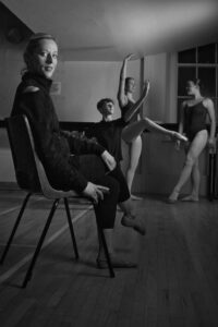 Black and white portrait of ballet dance teacher with pupils in background