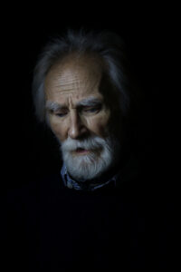 Portrait of older man with white beard looking down - headshot