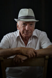Portrait of sitting older man with white shirt and straw hat