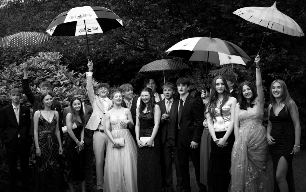 Young people raising umbrellas and prom gathering, North Yorkshire