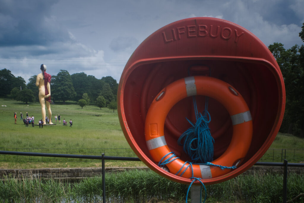 Distant view of Damien Hirst's The Mother Virgin with orange life buoy in the foreground at Yorkshire Sculpture Park