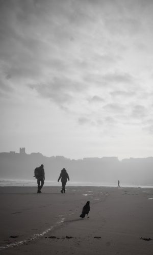 Walkers on North Bay beach, Scarborough, black and white